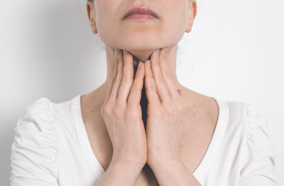 Angina. A woman holding her sore throat. Inflamed thyroid gland.